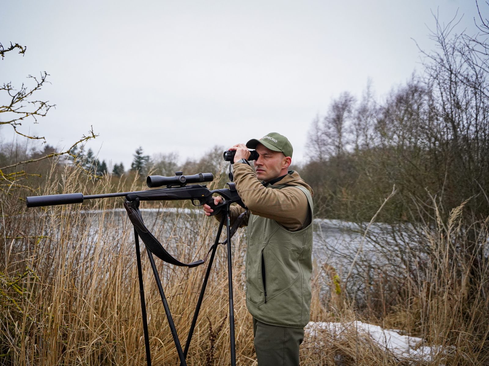 Jägare vid skjutstöd spanar över vattnet med HIKMICRO LYNX 3.0 termisk monokulär en grå höstdag
